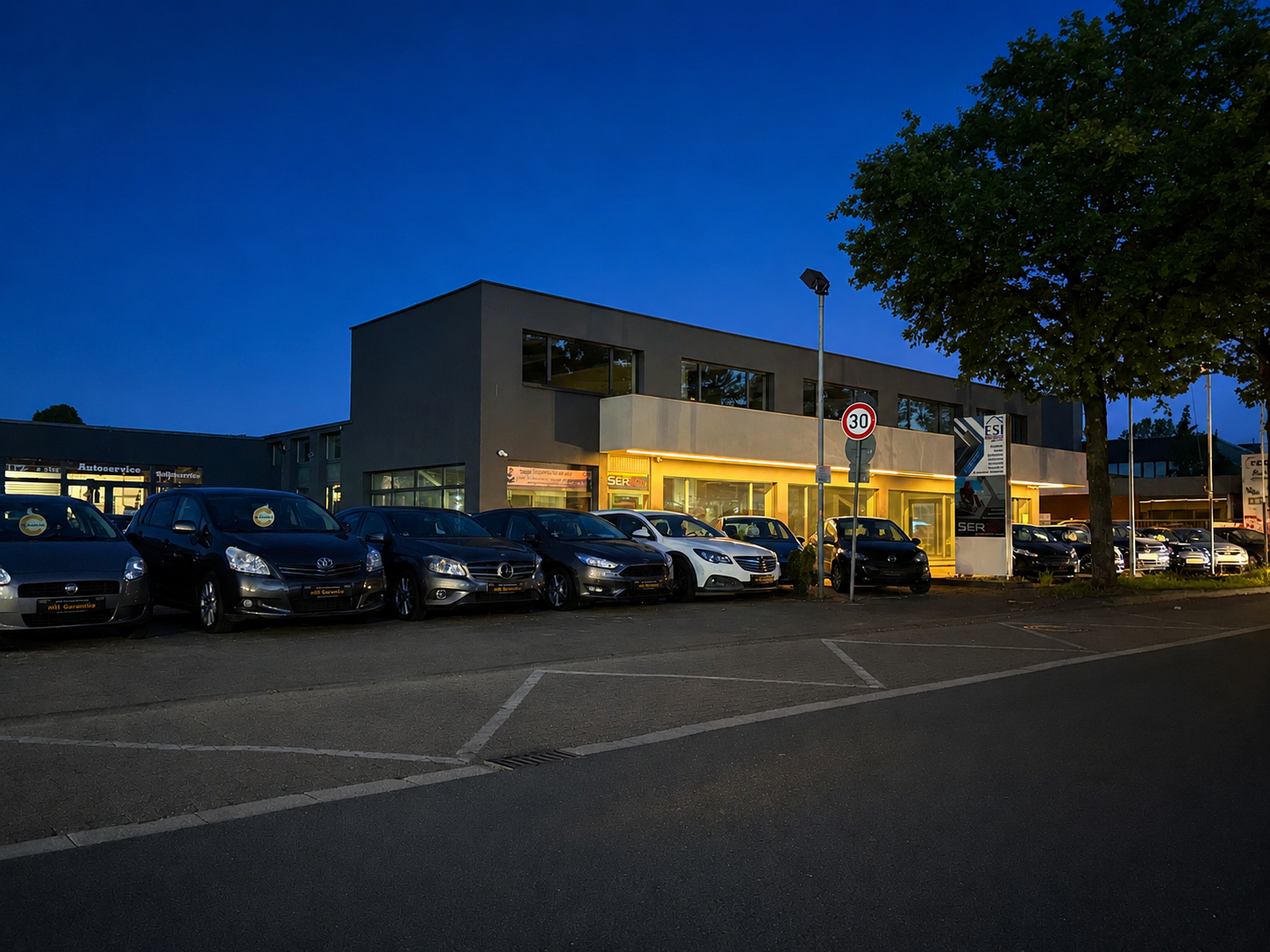 Autohaus Carthage — Panoramaansicht des Standorts in Gütersloh bei Abendlicht mit Fahrzeugreihe
